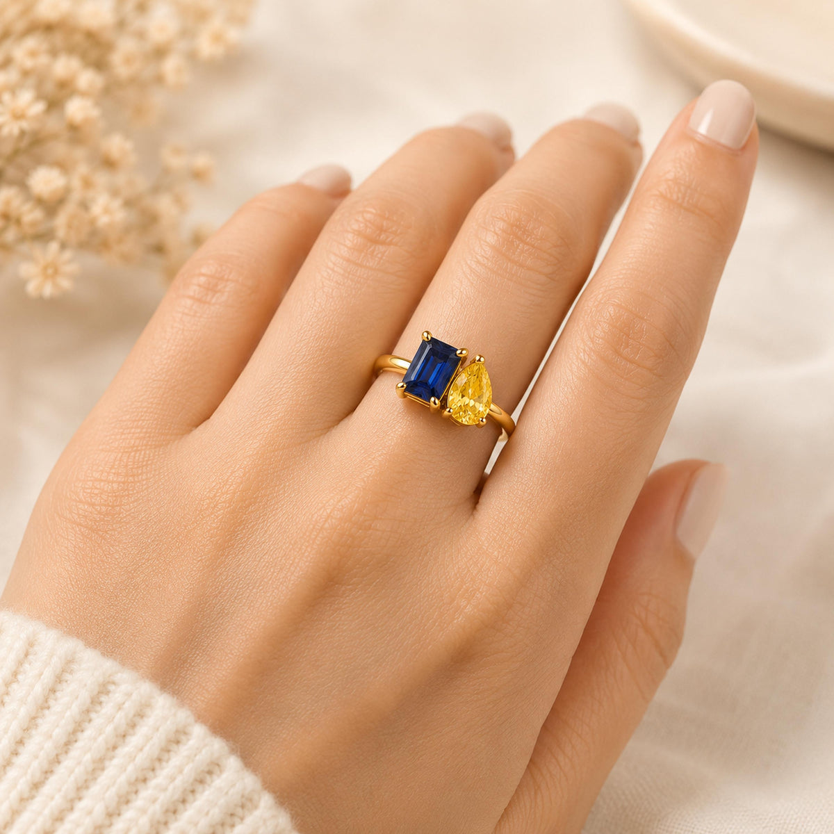 Two birthstone ring with blue and yellow stones worn on a hand