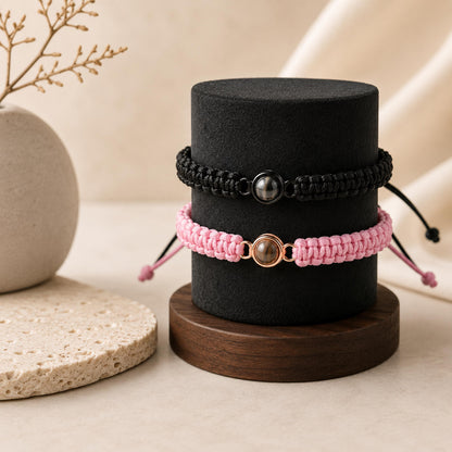 Matching black and pink projection bracelets for couples on a jewelry stand