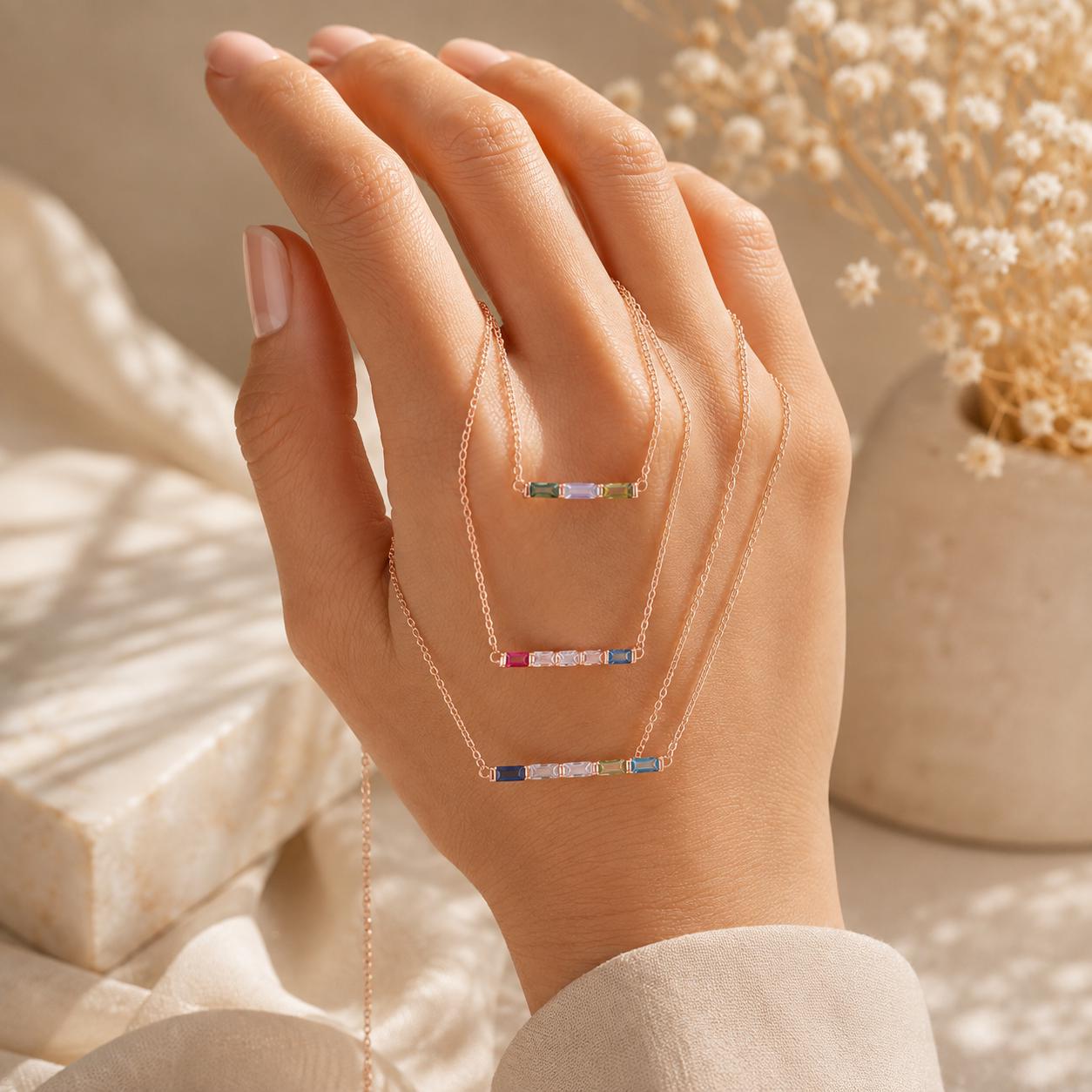 Rose gold personalized birthstone bar necklace draped over a hand