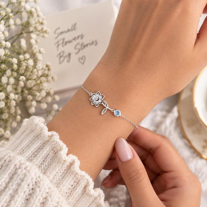 Silver tone birth flower bracelet worn on the wrist, close up