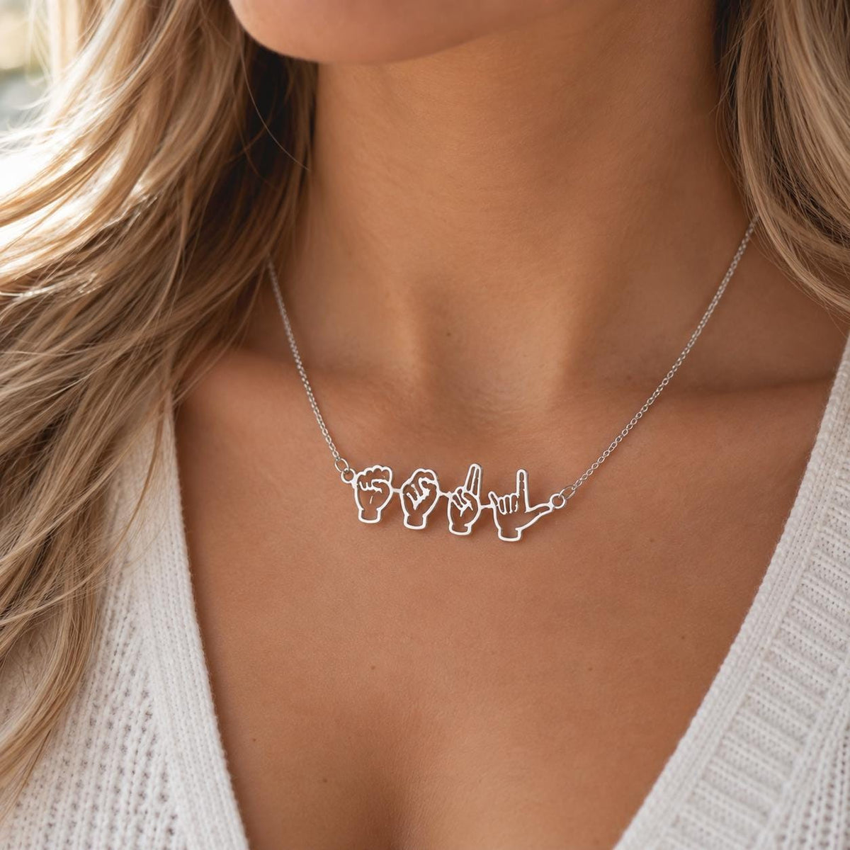 Silver tone sign language name necklace worn on the neck, close up