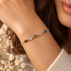 Gold tone leaf birthstone bracelet with colored stones worn on the wrist