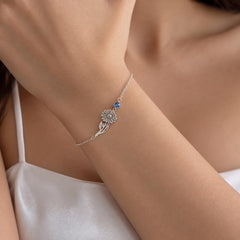 Silver tone birth flower bracelet with a birthstone worn on the wrist