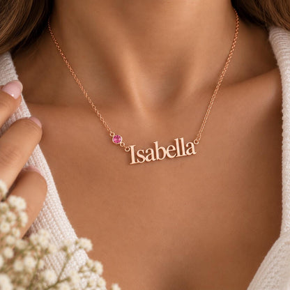 Rose gold tone name necklace with a pink stone worn on the neck