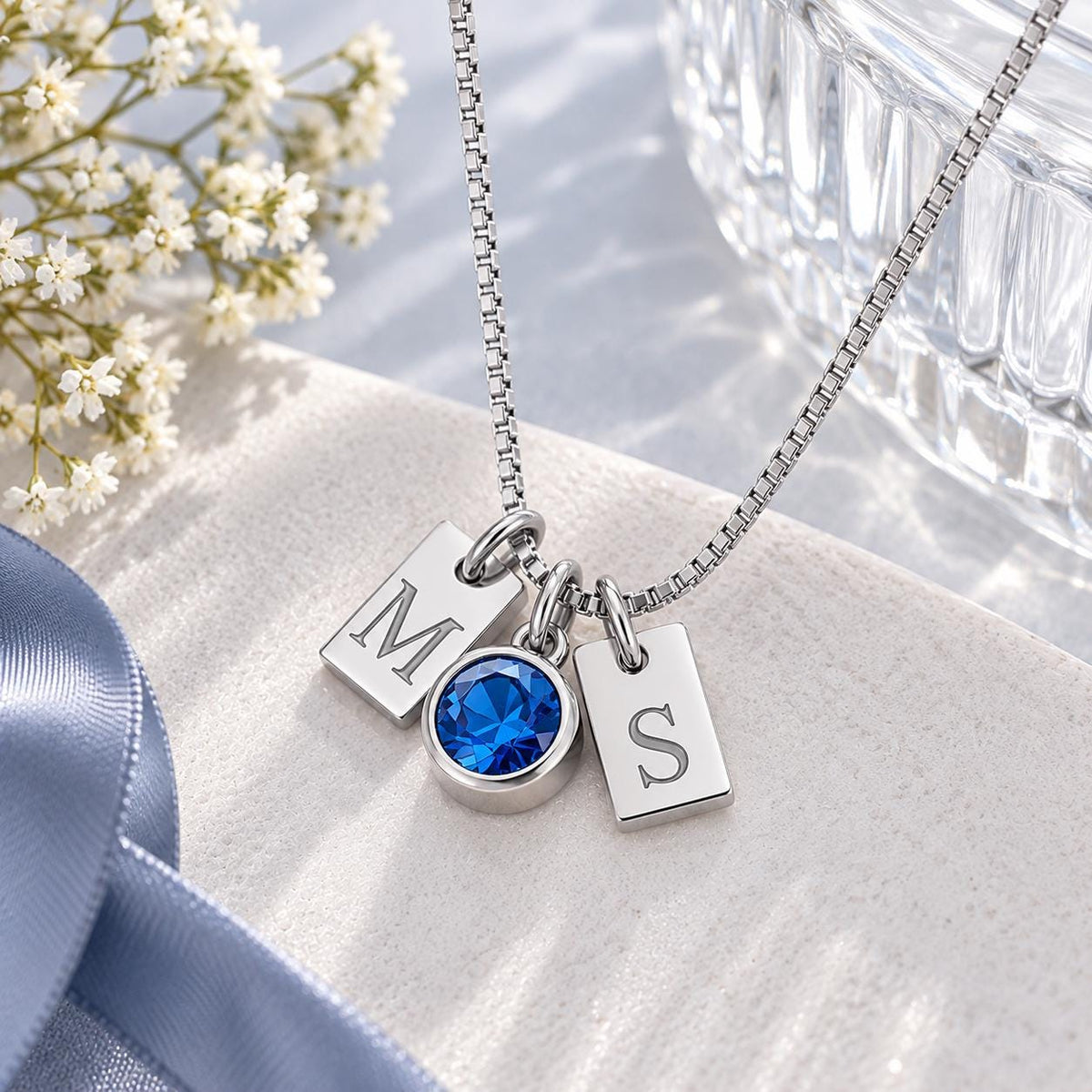 Silver tone initial tag necklace with a blue stone