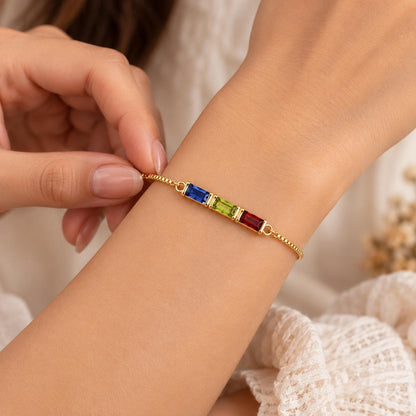 Gold tone baguette birthstone bracelet with colored stones worn on the wrist
