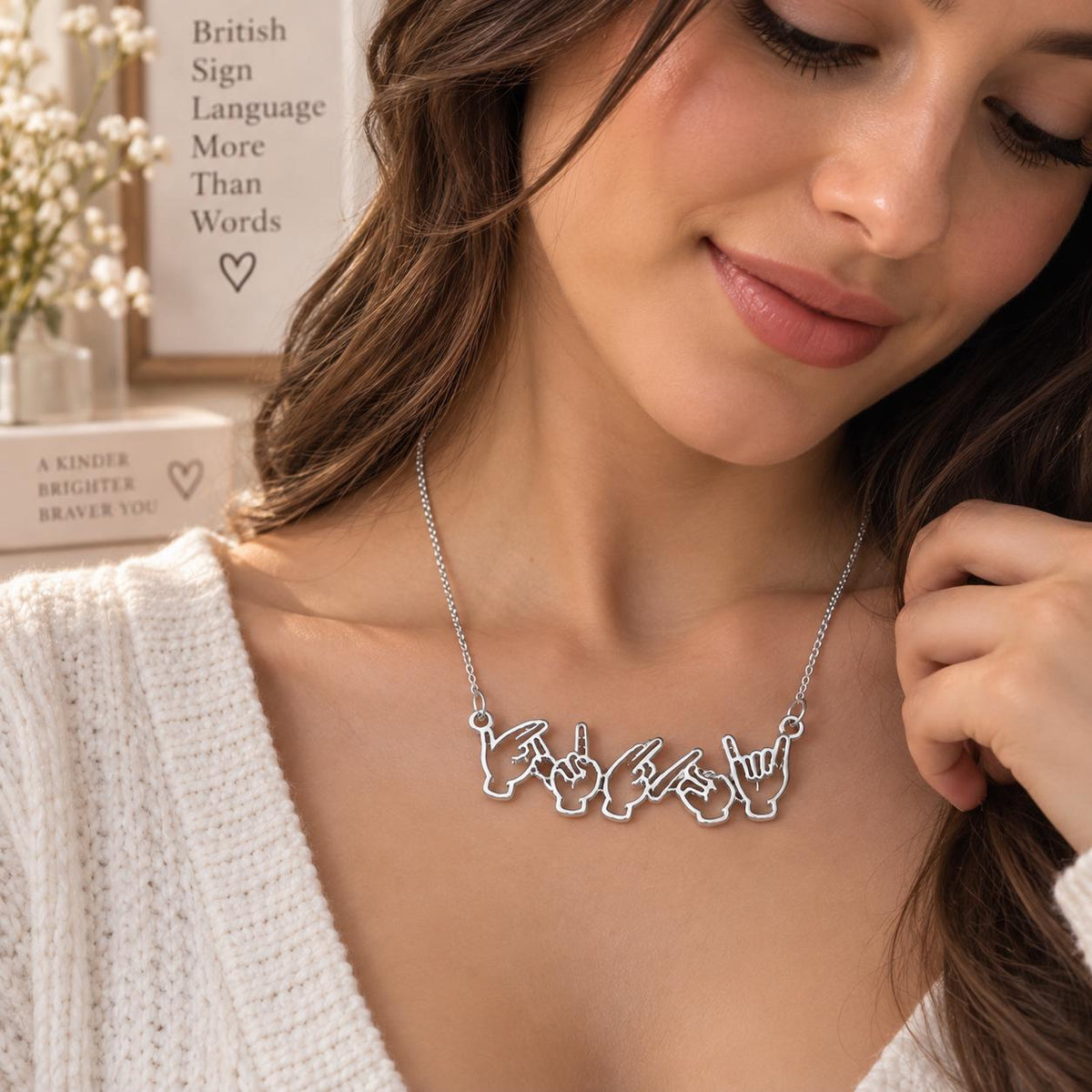 Silver tone sign language name necklace worn on the neck