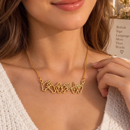 Gold tone sign language name necklace worn on the neck, close up
