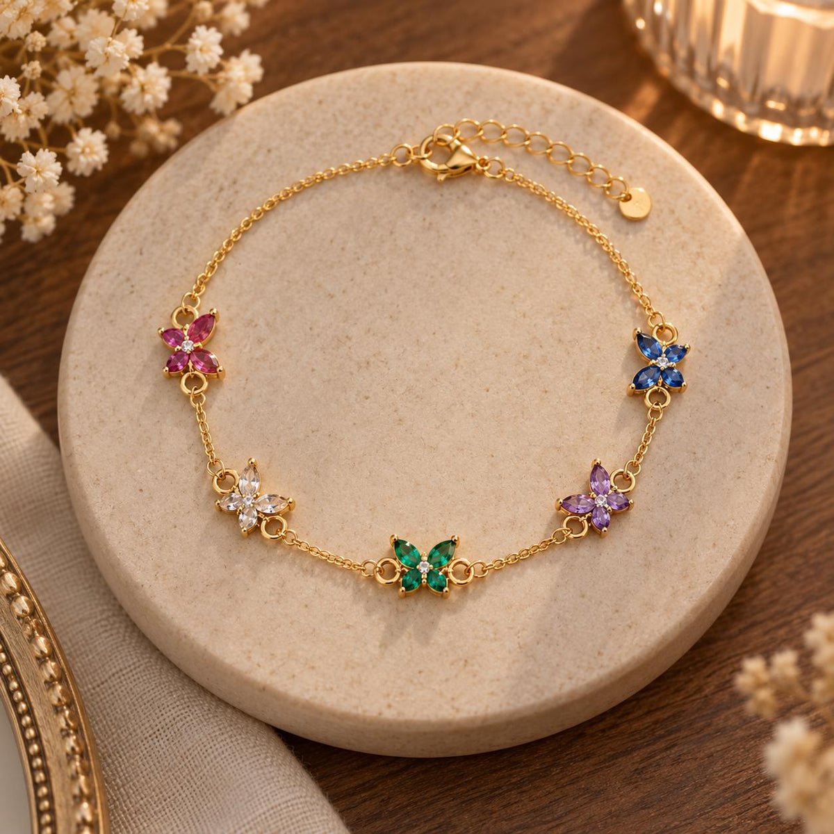 Gold tone butterfly birthstone bracelet on a jewelry dish