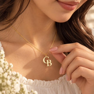 Gold tone double initial necklace with the letters C and B worn on the neck